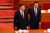 Chinese President and Premier stand before a table at meeting.