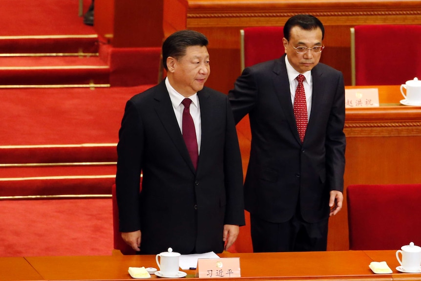 Chinese President and Premier stand before a table at meeting.