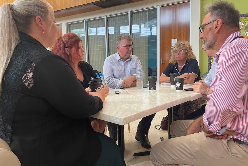 A group of people sit around a table, talking.