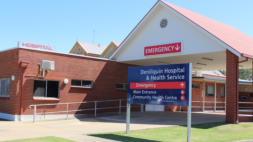 Brick building next to talk white car port with blue sign out the front "Deniliquin Hospital "