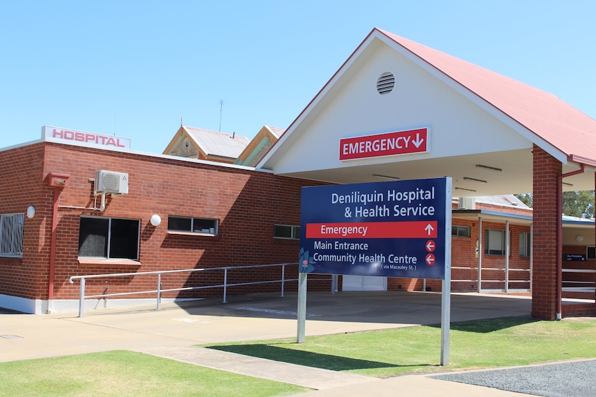 Brick building next to talk white car port with blue sign out the front "Deniliquin Hospital "