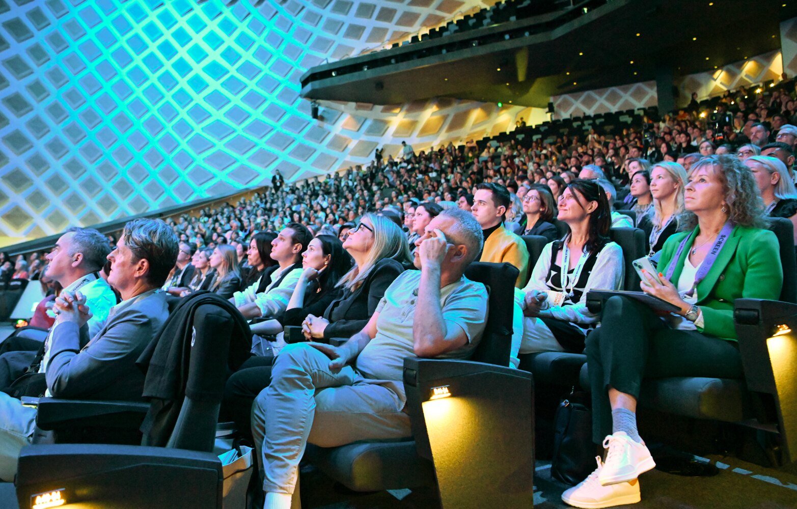 An audience of people looking on with faces focused on stage