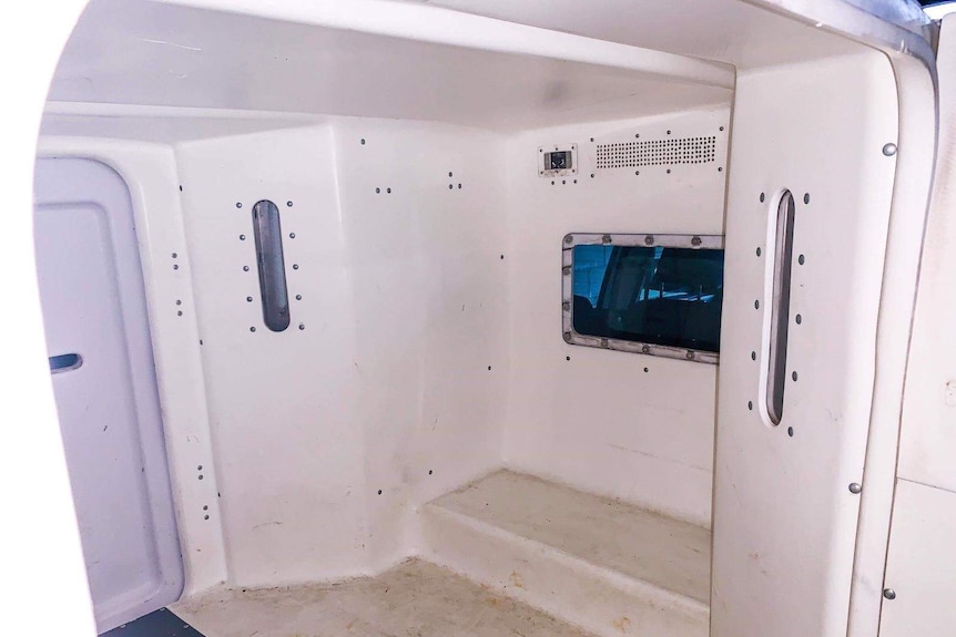 The interior of a Tasmanian police van, showing a step for sitting on and no seatbelts.