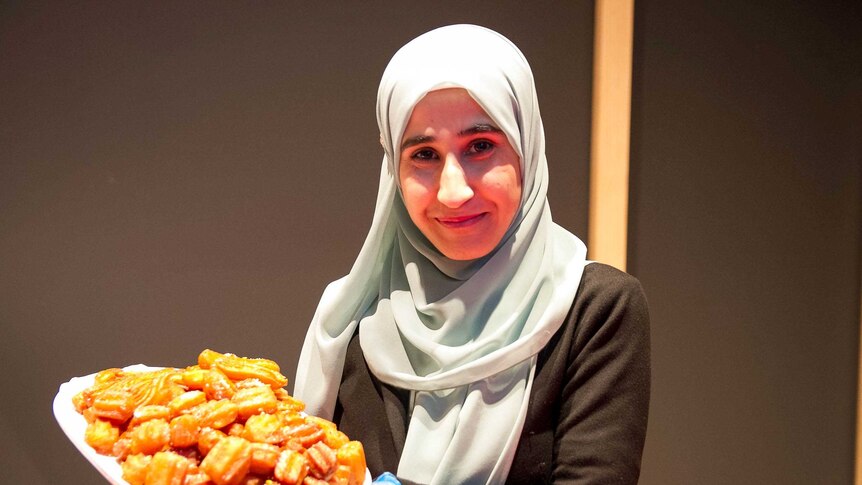 A young woman holds a tray of Middle Eastern deep fried sweets.