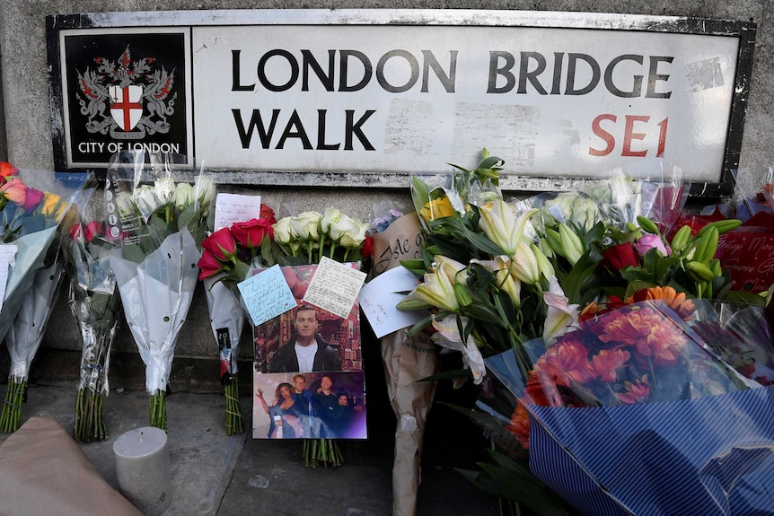 Flowers lay under a sign for the London Bridge Walk