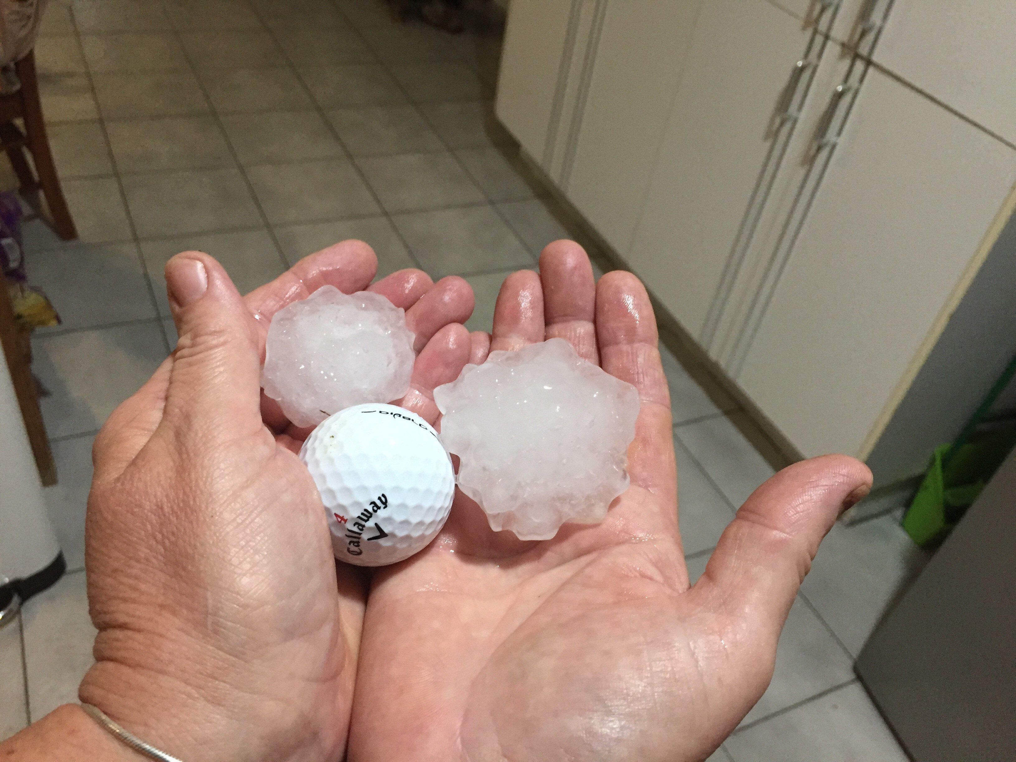 Rockhampton resident shows giant hail next to a golf ball after a storm battered her property.