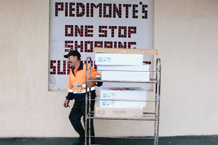 A man pulls a trolley full of fresh stock into the store.