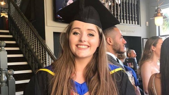 Grace Millane wearing graduation robes and smiling.