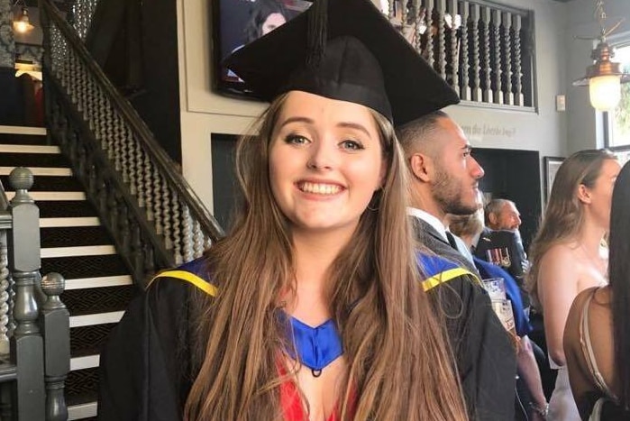 Grace Millane wearing graduation robes and smiling.