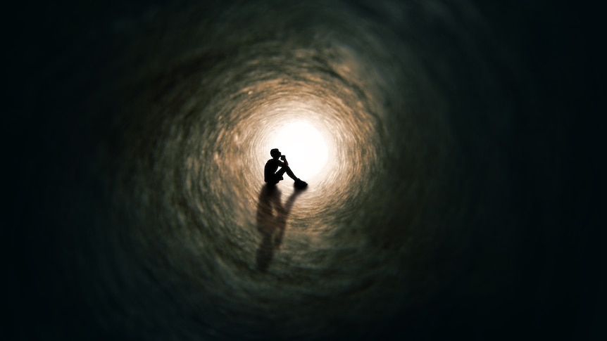 Dark silhouette in tunnel with light at the end.