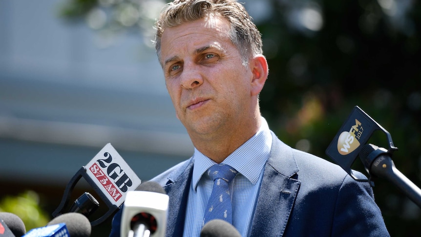 man in suit in front of microphones