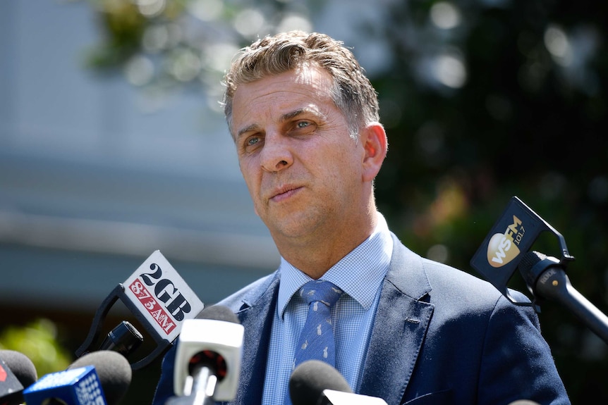 man in suit in front of microphones