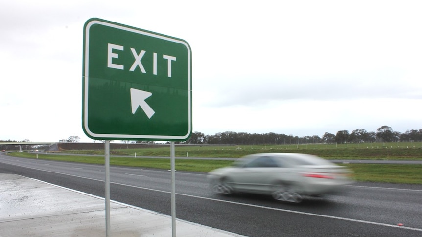 A car drives past a freeway exit sign.