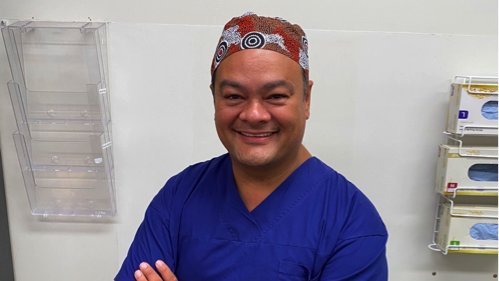 Kelvin Kong wearing blue scrubs and smiling