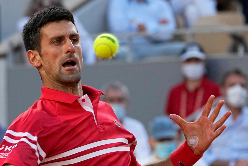 Novak Djokovic leans back and watches the ball