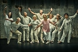 A group of nine older people wearing white in various dance poses