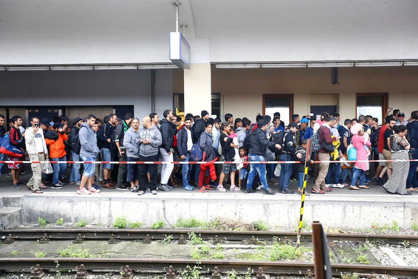 Migrants walk along a railway station platform in Vienna
