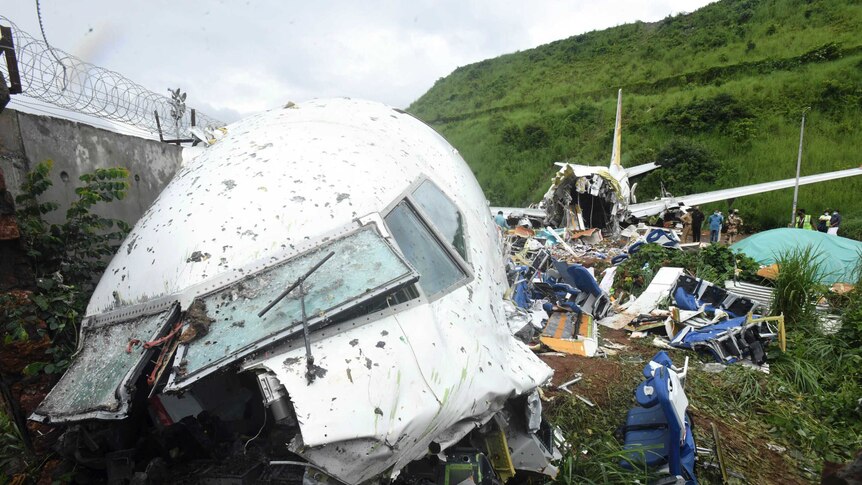 People stand by the debris of the Air India Express flight, which is broken into two pieces.