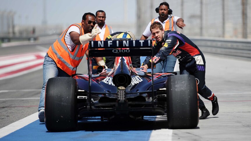 Sebastian Vettel helps push his car back to the pits