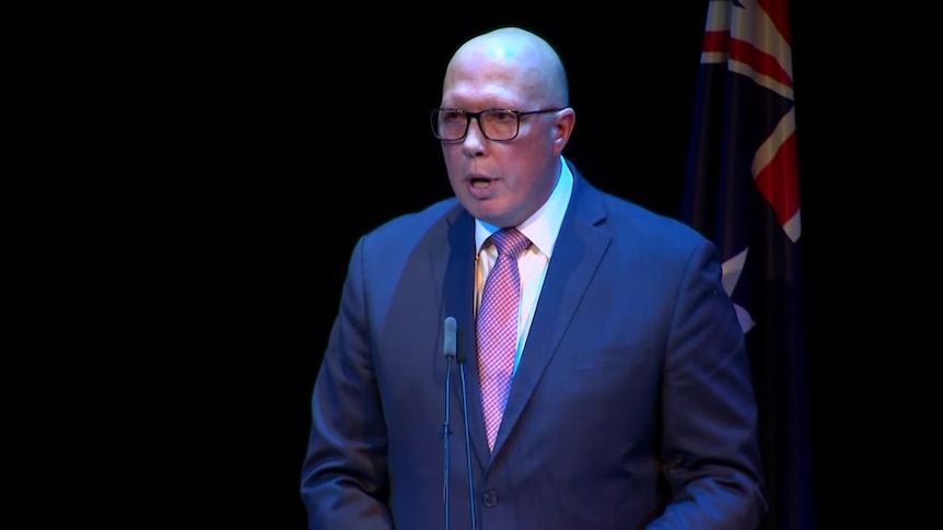 Peter Dutton delivers a speech with an Australian flag behind him.
