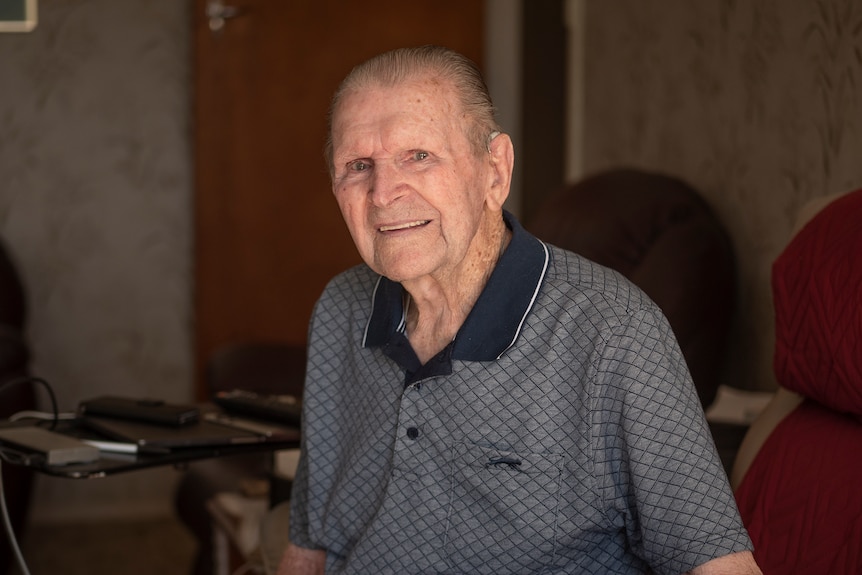 An elderly man smiling inside his home.