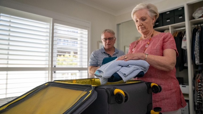 A woman and a man packing in a bedroom.