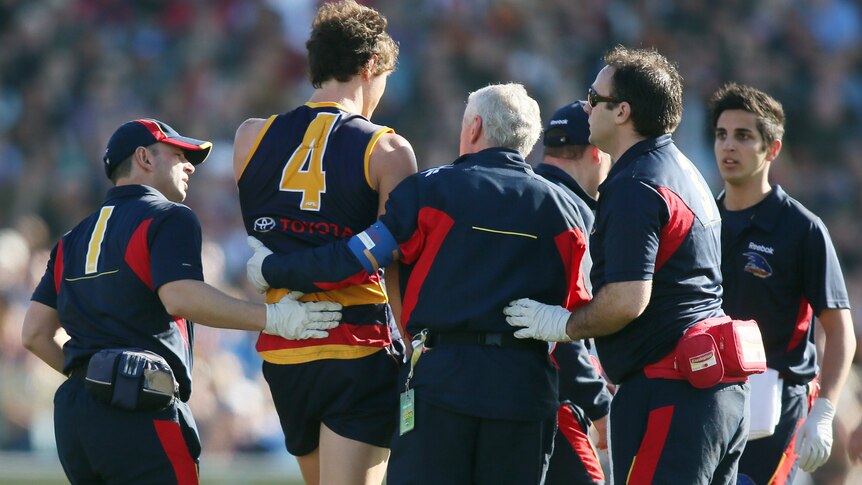 Adelaide's Kurt Tippett is helped from the field after being concussed against West Coast last year.