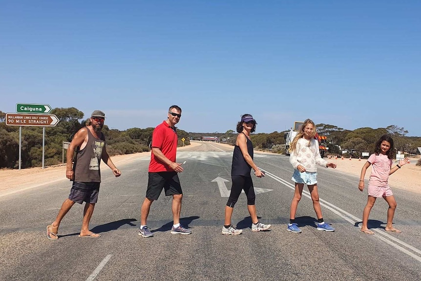 People walking across an outback highway.