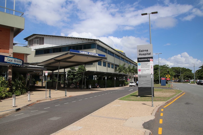 A modern exterior of a hospital and its front entrance beside a road.