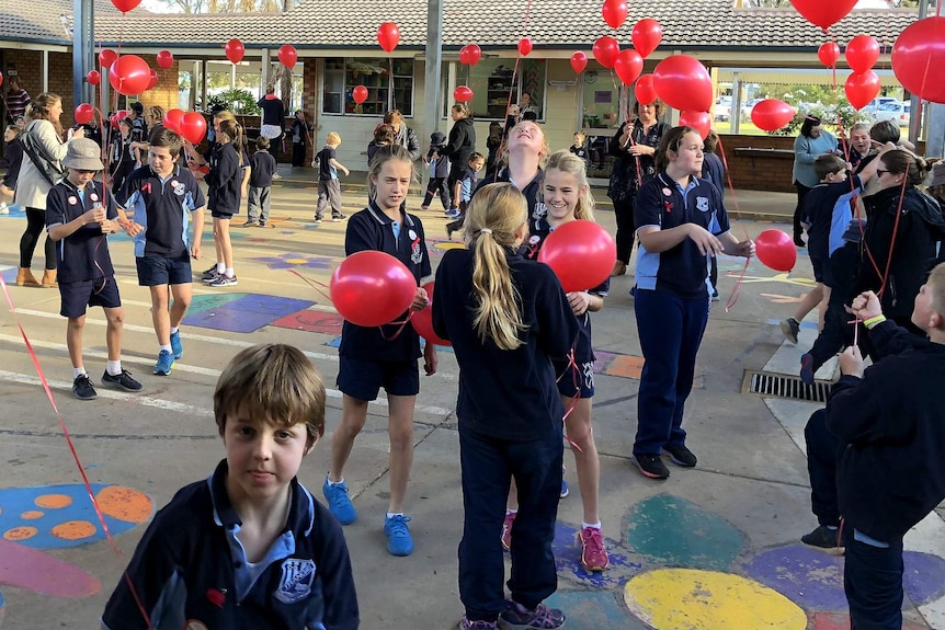 Primary school students at Trangie, playing in the quadrangle with red balloons.