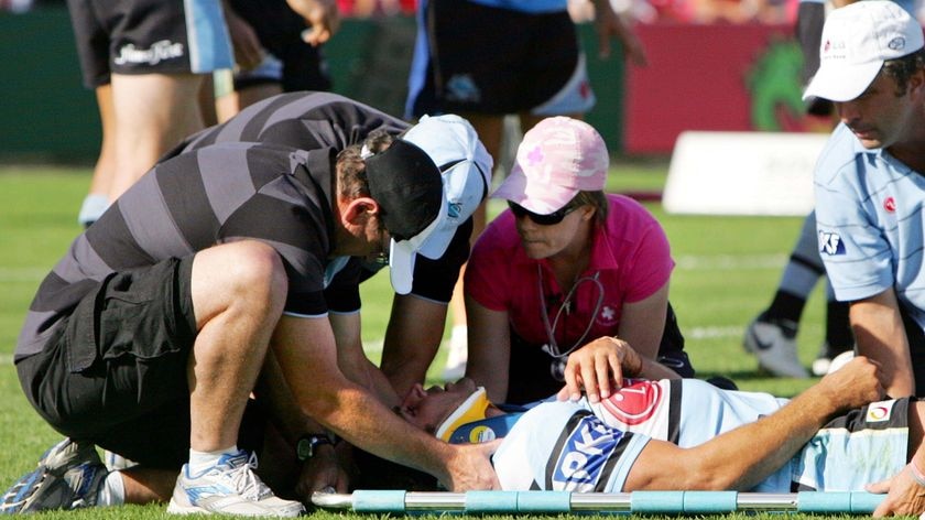 A rugby league player on a stretcher attended by officials