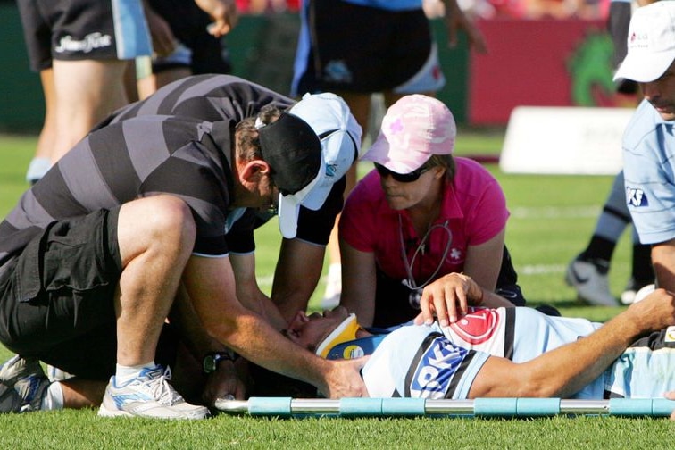 A rugby league player on a stretcher attended by officials