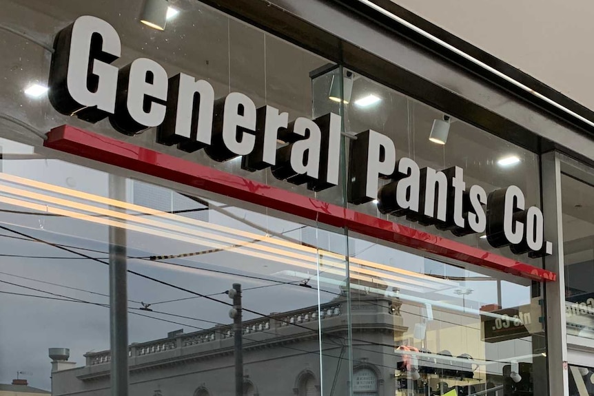 Storefront of a clothing shop with yellow discount sign on the front window