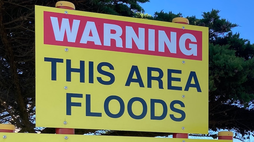 A sign says 'Warning: This area floods. The community is opposed to development on these wetlands"