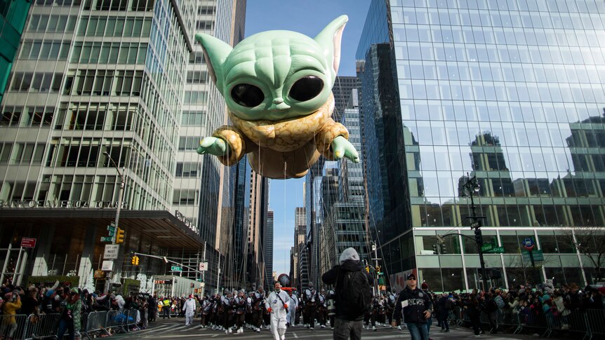 A giant inflatable of Baby Yoda floats above a parade in New York City