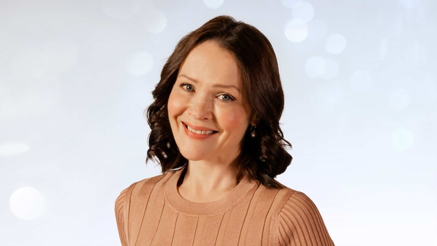 Greta Bradman portrait; her hair is softly curled and she is wearing a beige sweater.