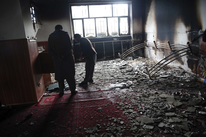 Afghan Sikhs inspect a blackened wall inside a Sikh house of worship.