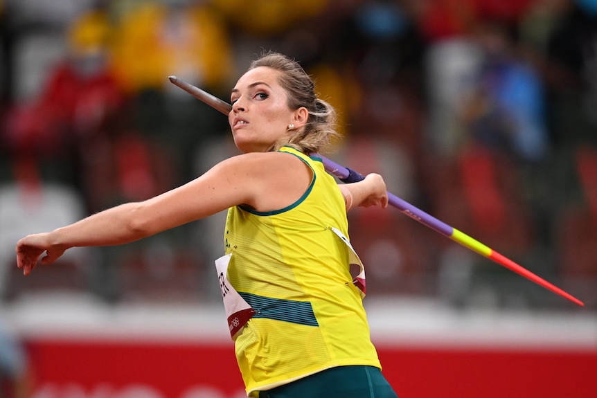 An Australian female athletes holds the javelin next to her head as she prepares to throw.