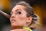 An Australian female athletes holds the javelin next to her head as she prepares to throw.