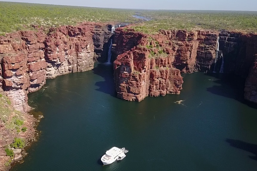 Distance shot of King George Falls in the northern Kimberley with a white boat in the foreground.