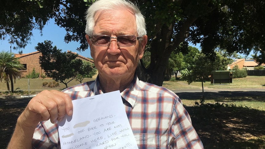 An older man holds up a letter