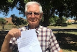 An older man holds up a letter