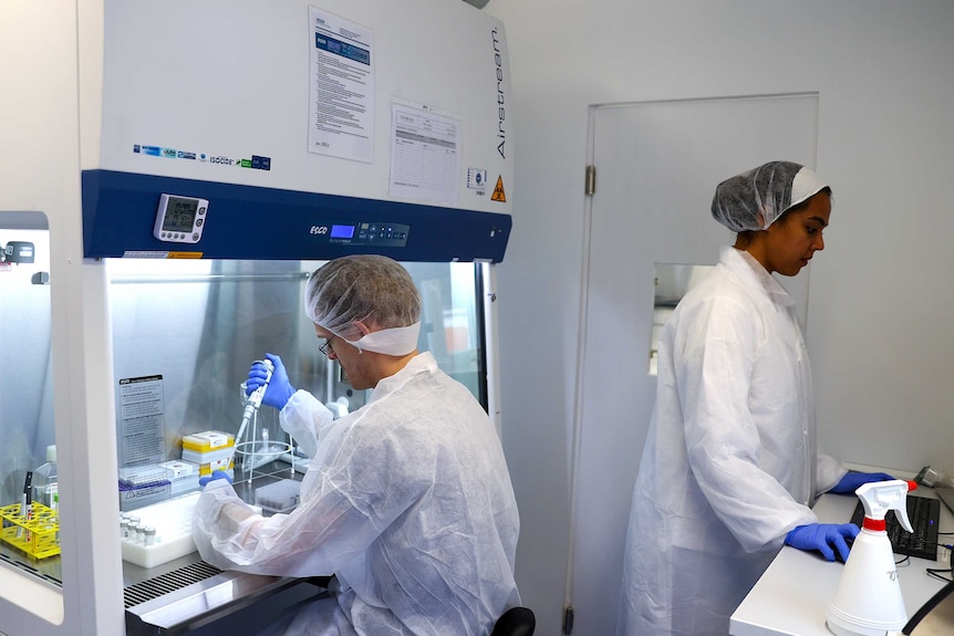 A man in lab gear doing experiments in a lab