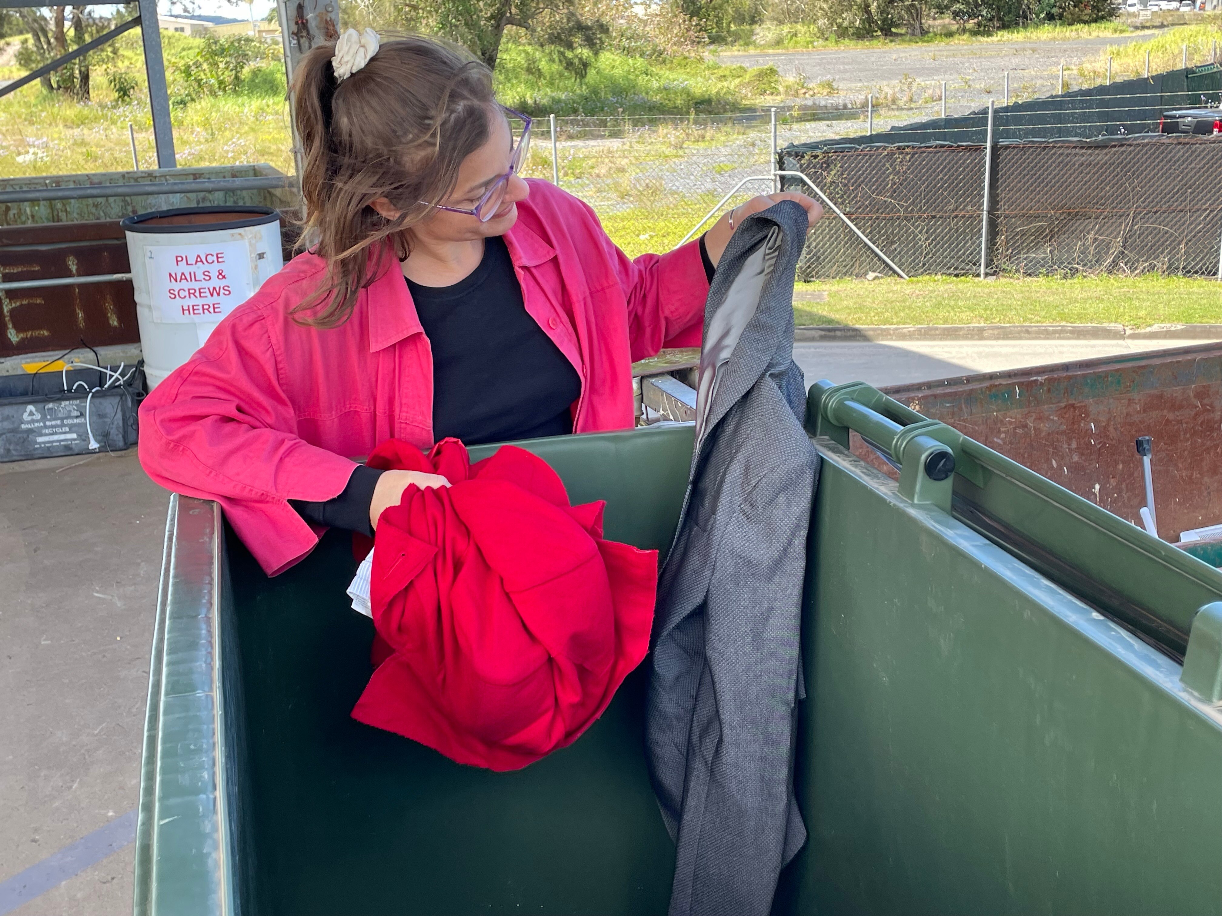 Woman sorts through clothing bin.