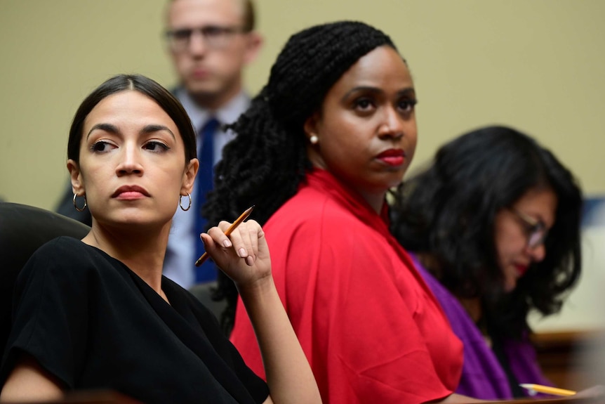 Three women listen to proceedings at the house oversight committee hearing