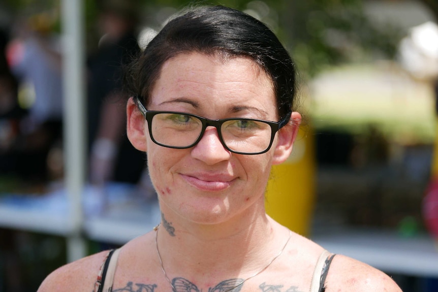 Woman with black hair, glasses and tattoos