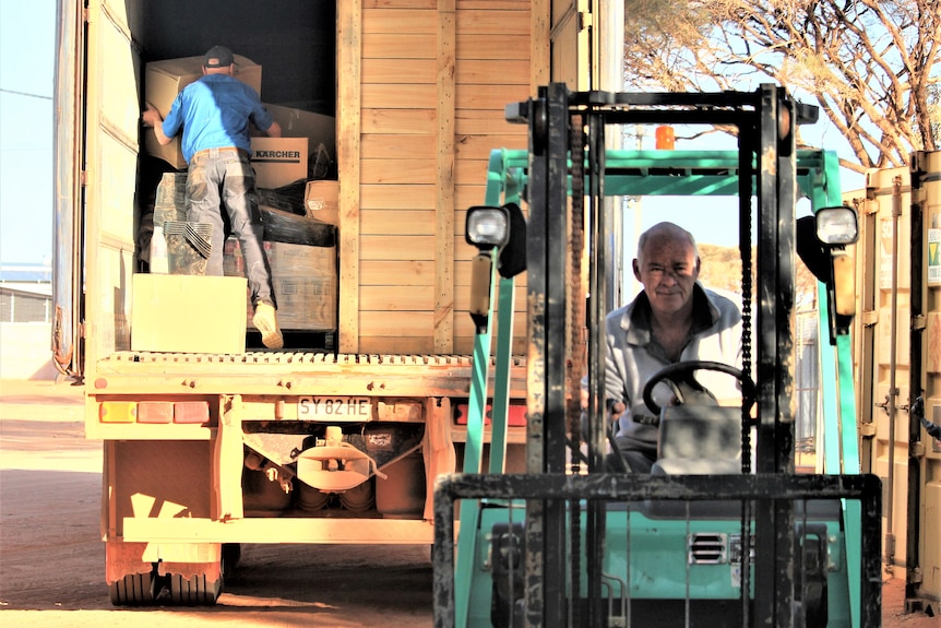 A man drives towards the camera in a forklift, Mr Mozol's back is to the camera as he unloads things