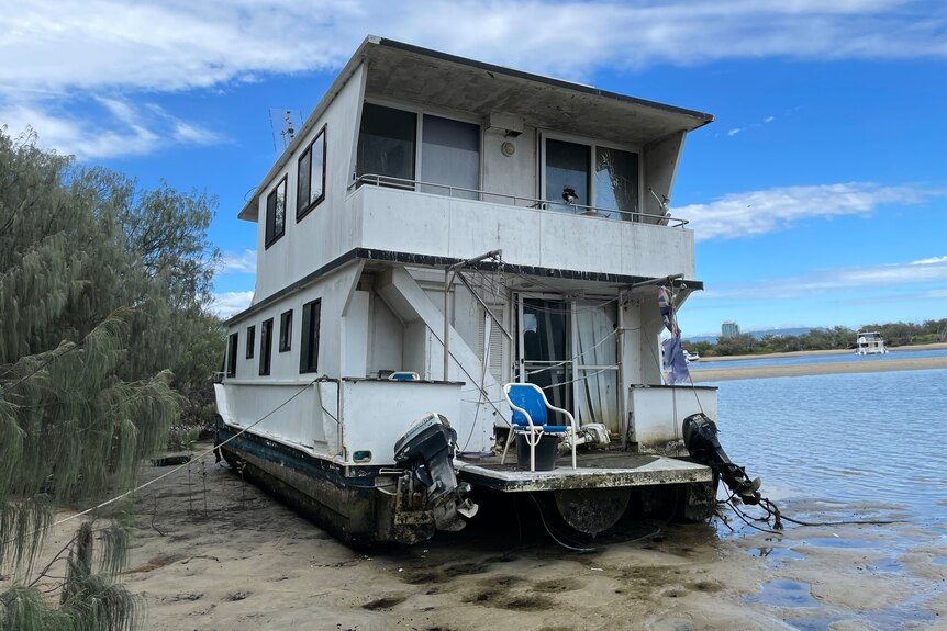 a two-storey house boat beached on a sand bank at low tide