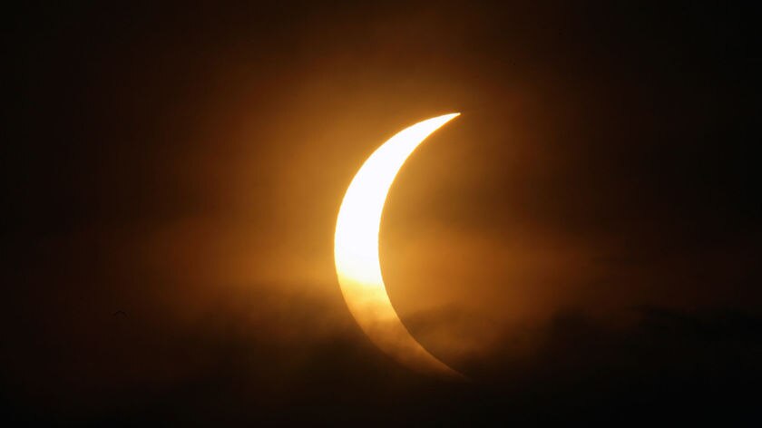 The moon passes between the sun and earth amid monsoon clouds during a solar eclipse in Delhi