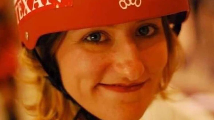 A woman wearing an orange helmet smiles